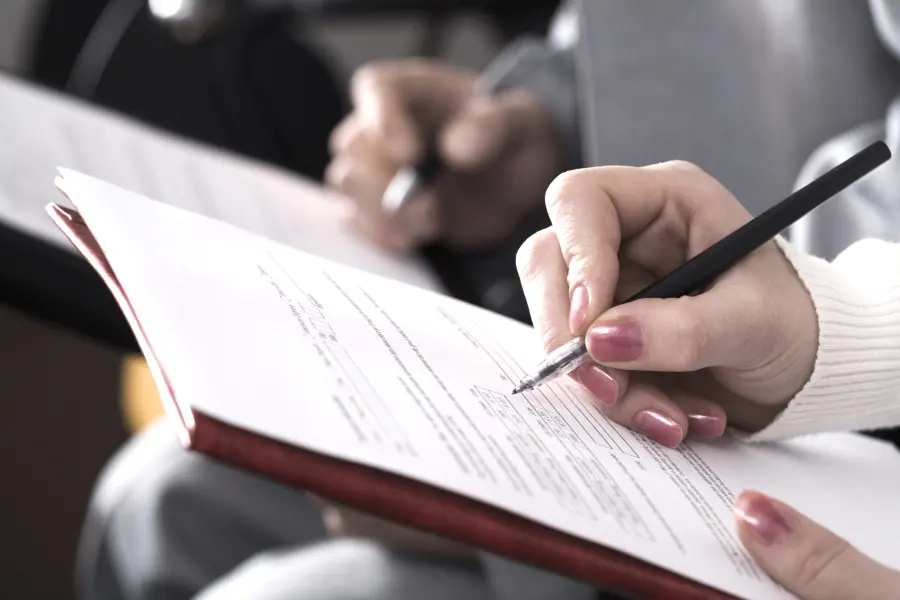 A parent filling out patient paperwork with a pen
